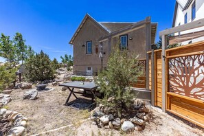 A house with a patio, a wooden fence, and a small tree.