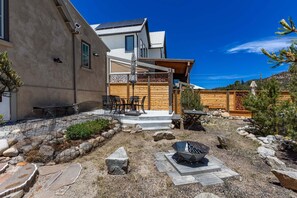 A modern house with a patio, outdoor seating, and a fire pit.