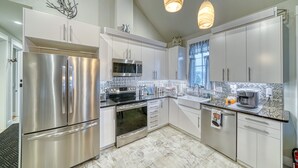 Una cocina moderna con electrodomésticos de acero inoxidable, armarios blancos y un salpicadero con diseño.