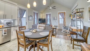Una cocina amplia con electrodomésticos modernos, un comedor con una mesa redonda y sillas, y una sala de estar con sofá y televisor.