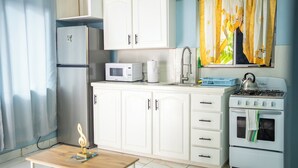 A kitchen with white cabinets, a microwave, a stove, and a sink.