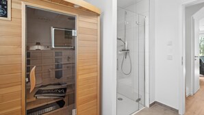 A sauna with a wooden exterior and glass doors, a shower area with glass walls, and a visible control panel. - 2 bedroom awesome home in Tossens (Tossens)