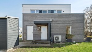 A modern two-story building with a flat roof, a central entrance with a door, and a small porch area. - 2 bedroom awesome home in Tossens (Tossens)