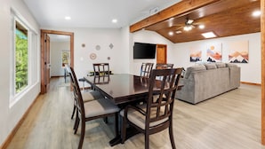 A dining area with a wooden table and chairs, a sofa, and artwork on the walls. - MTNSIDE Cabin with VIEWS by LYNX LAKE 20 min to TOWN (Prescott)