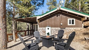 A cabin with a stone foundation, a green roof, and a covered patio area with Adirondack chairs and a fire pit. - MTNSIDE Cabin with VIEWS by LYNX LAKE 20 min to TOWN (Prescott)