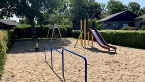 Un parque infantil con arena, un tobogán y columpios.