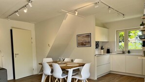 Eine moderne Küche mit weißen Schränken, einem Holztisch und weißen Stühlen.