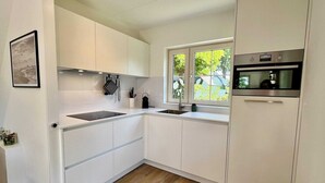 Eine moderne Küche mit weißen Schränken, einem Einbauofen und einem Fenster, das für natürliches Licht sorgt.