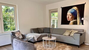 Ein modernes Wohnzimmer mit einem grauen Sofa, einem runden Couchtisch und einem großen Gemälde an der Wand.