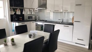 Eine moderne Küche mit weißen Schränken, einer schwarzen Arbeitsplatte und einem Essbereich mit Tisch und Stühlen.