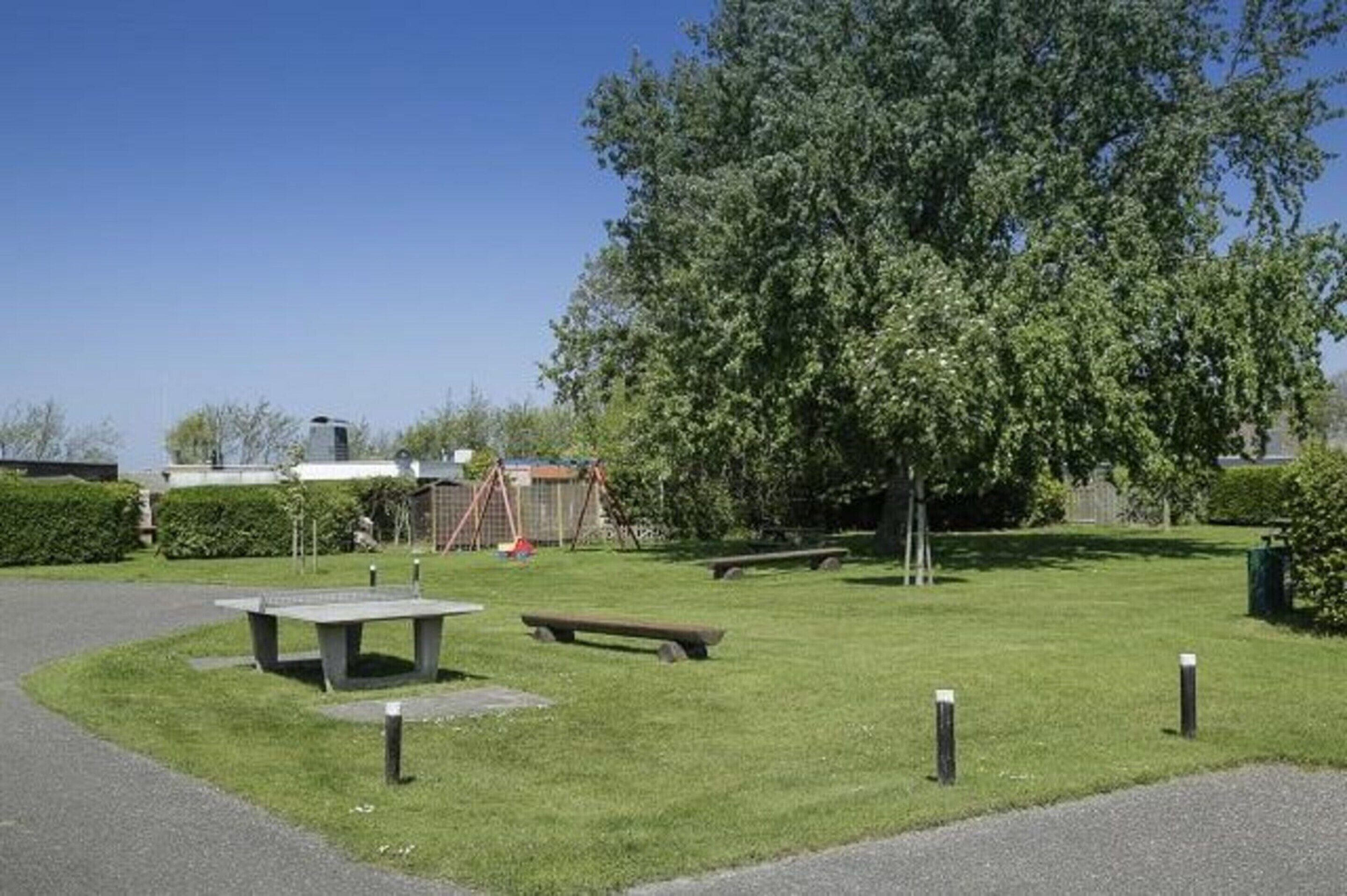 A park with a picnic table, benches, and a playground.