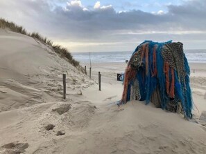 A sandy beach with a large, colorful, abstract sculpture in the foreground. - Nice Bungalow for Family Vacation (Sint Maartensvlotbrug)