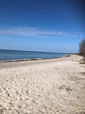 A sandy beach with a clear sky and calm sea.