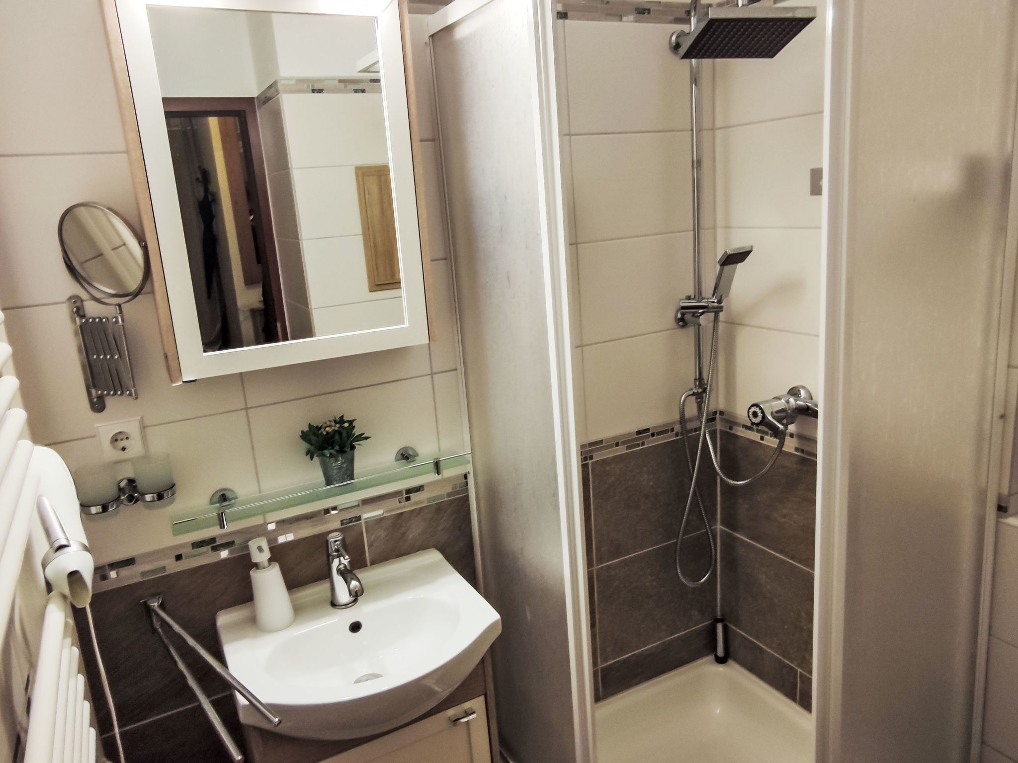Une salle de bain moderne avec un lavabo blanc, une étagère en verre, un miroir et un espace douche.