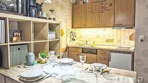 A modern kitchen with wooden cabinets, a built-in dishwasher, and a dining area set for a meal. - Bocksbergperle 3 by Interhome (Hahnenklee)