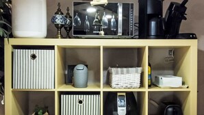A shelf with various items including a speaker, a microwave, a coffee maker, a phone, and a basket. - Bocksbergperle 3 by Interhome (Hahnenklee)