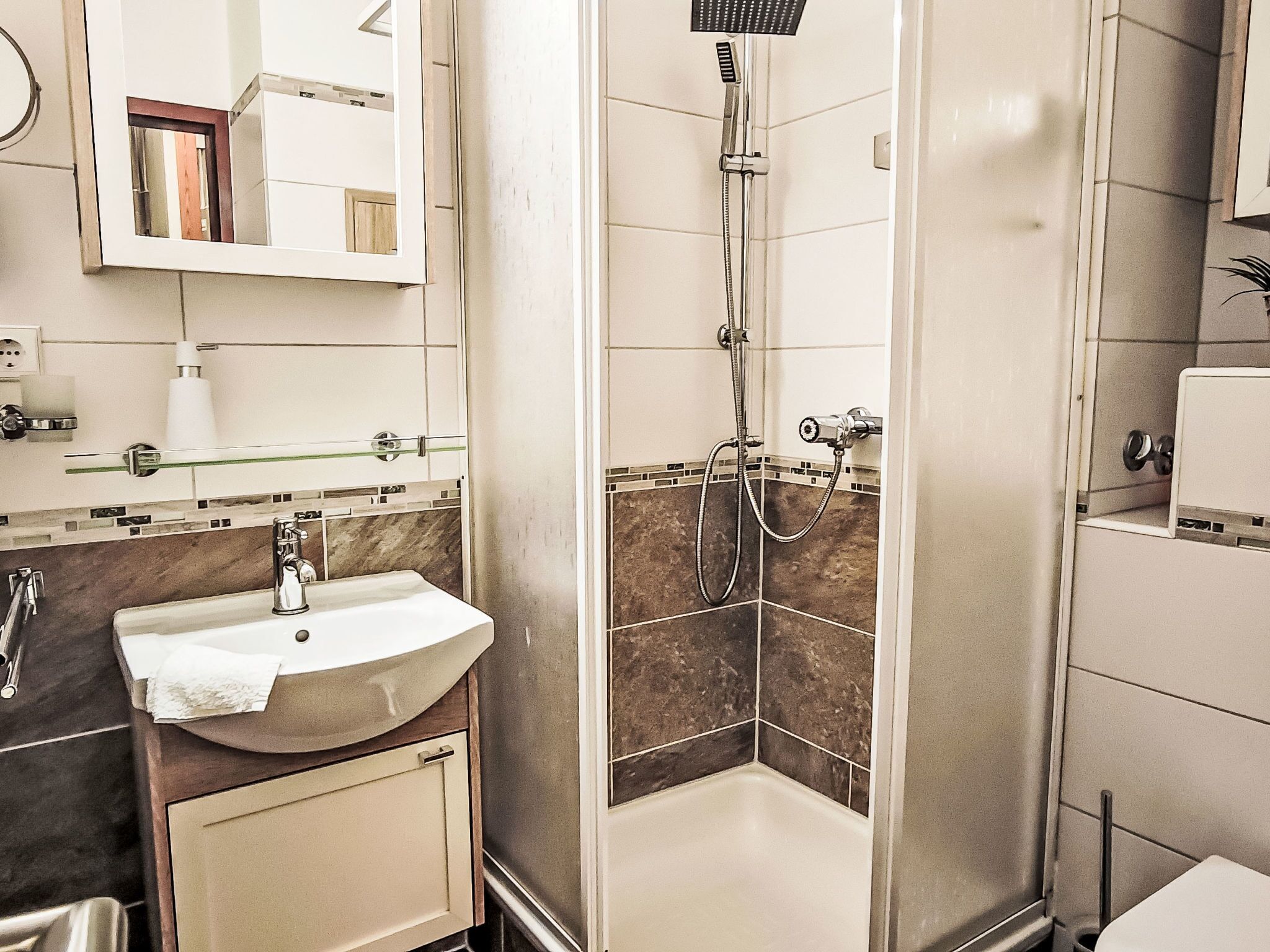 A modern bathroom with a sink, mirror, and shower.