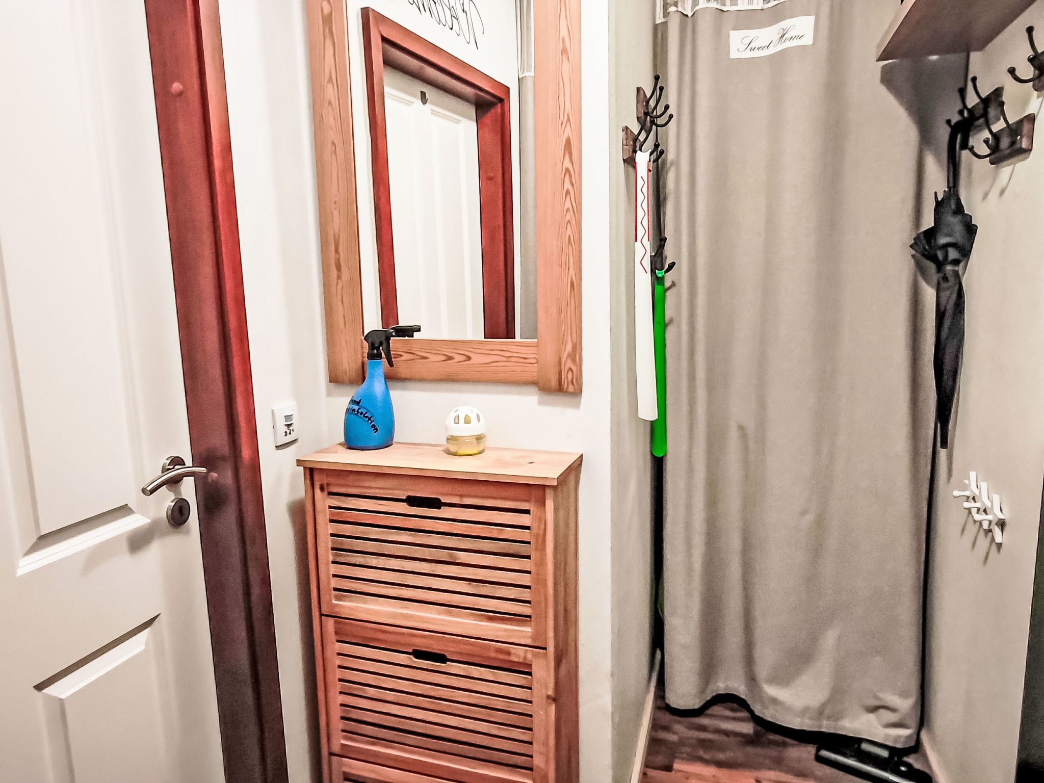 Une salle de bain avec un meuble en bois, un miroir, un rideau de douche et un porte-serviettes.