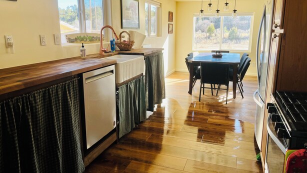 Una cucina con piani di lavoro in legno, lavastoviglie, tavolo da pranzo con sedie e frigorifero.