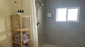 Un bagno con doccia, una finestra e uno scaffale con asciugamani.