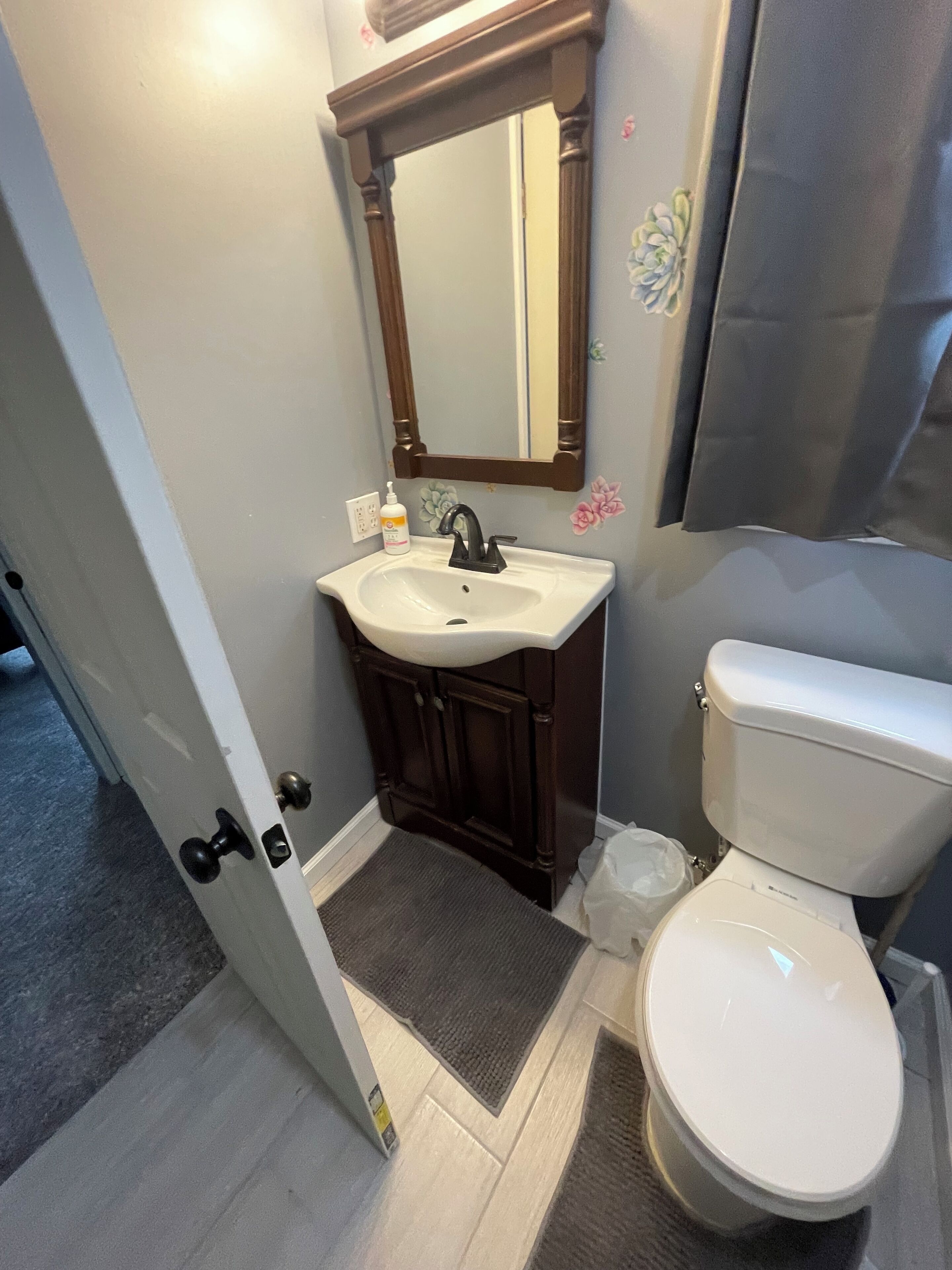 Een badkamer met een wit wastafel, een donker houten wastafelmeubel, een spiegel en een toilet.