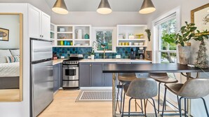 A modern kitchen with stainless steel appliances, a central island with bar stools, and pendant lighting.