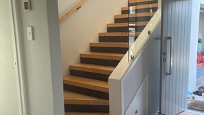 A modern staircase with wooden steps and glass railings, leading to a second floor. - HILLTOP, CENTRAL, QUIET, LOCATION WITH STUNNING LAKE AND MOUNTAIN VIEWS. (Taupō)