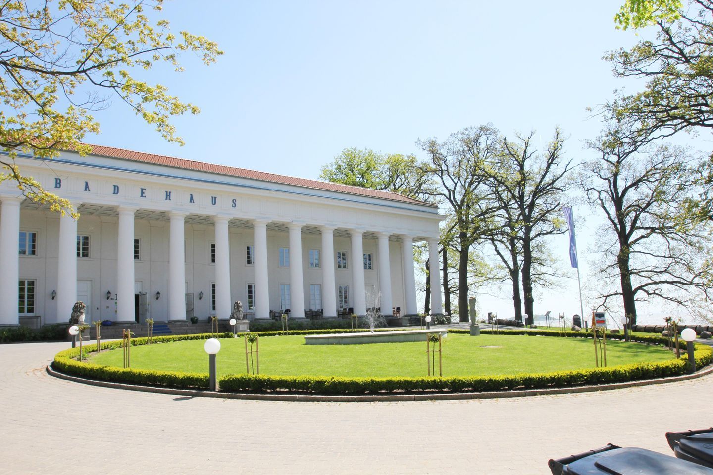 A large white building with columns, a well-manicured lawn, and a flag.