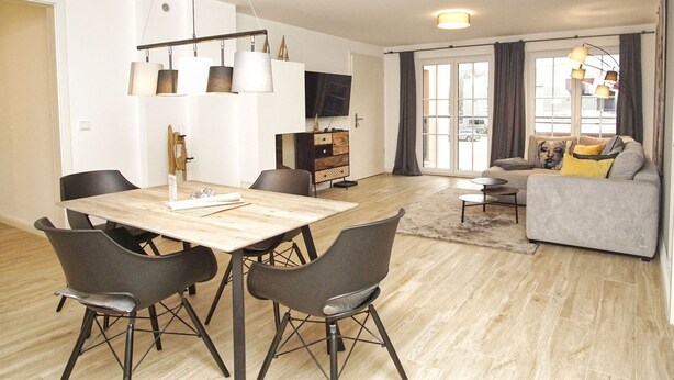 Uma sala de estar moderna com área de jantar, sofá e televisão.