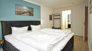 Quarto de hotel com uma cama grande, uma mesa de cabeceira, um espelho e vista para o corredor.