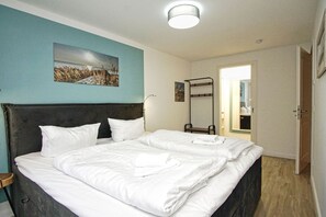 A hotel room with a large bed, a bedside table, a mirror, and a view of the hallway. - Close to the sailing harbor - Alte Fischfabrik Lauterbach FeWo 07 RELAXEN in Lauterbach (Putbus)