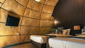 Une chambre moderne dotée d’un décor mural géométrique original, d’un téléviseur à écran plat fixé au mur et d’un lit agrémenté de plusieurs oreillers.