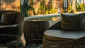 Un espace extérieur aménagé dans un style tropical, avec des meubles en osier et des structures dotées de toits de chaume.