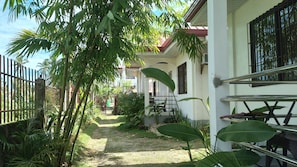 A narrow pathway leading to a building with a white exterior and a red roof. - Yayay Siargao (General Luna)