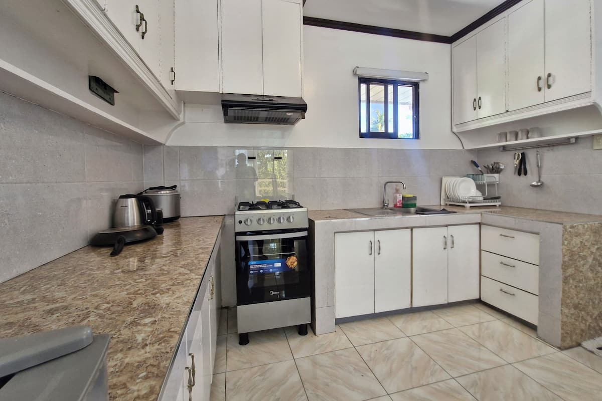 A kitchen with white cabinets, a gas stove, an oven, a sink, and a window.