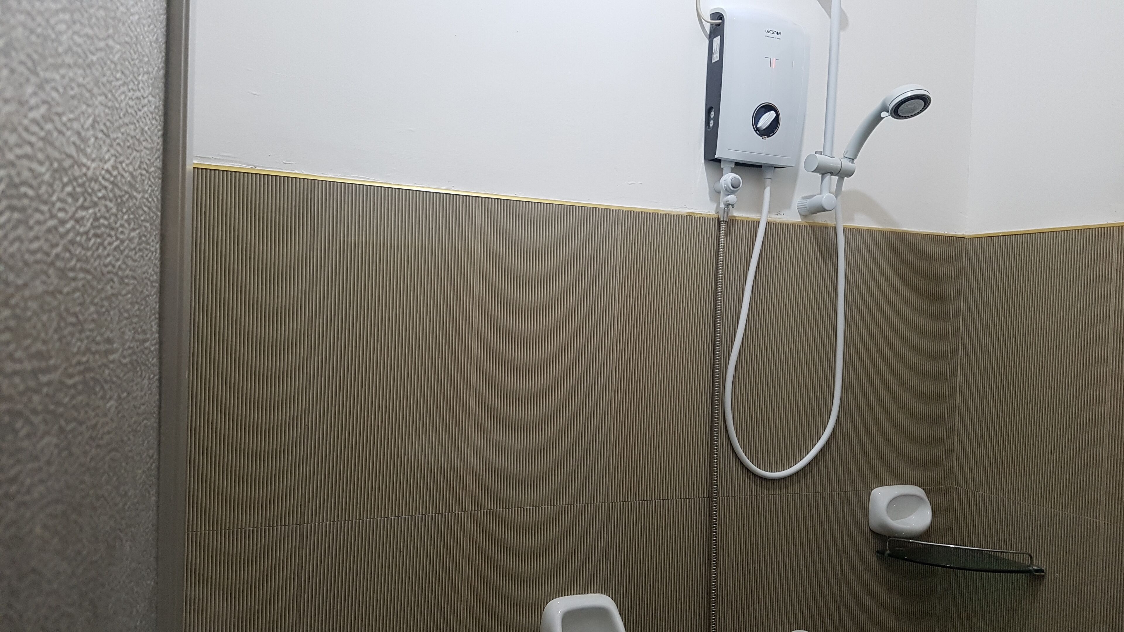 A bathroom with a shower, a toilet, and a urinal.