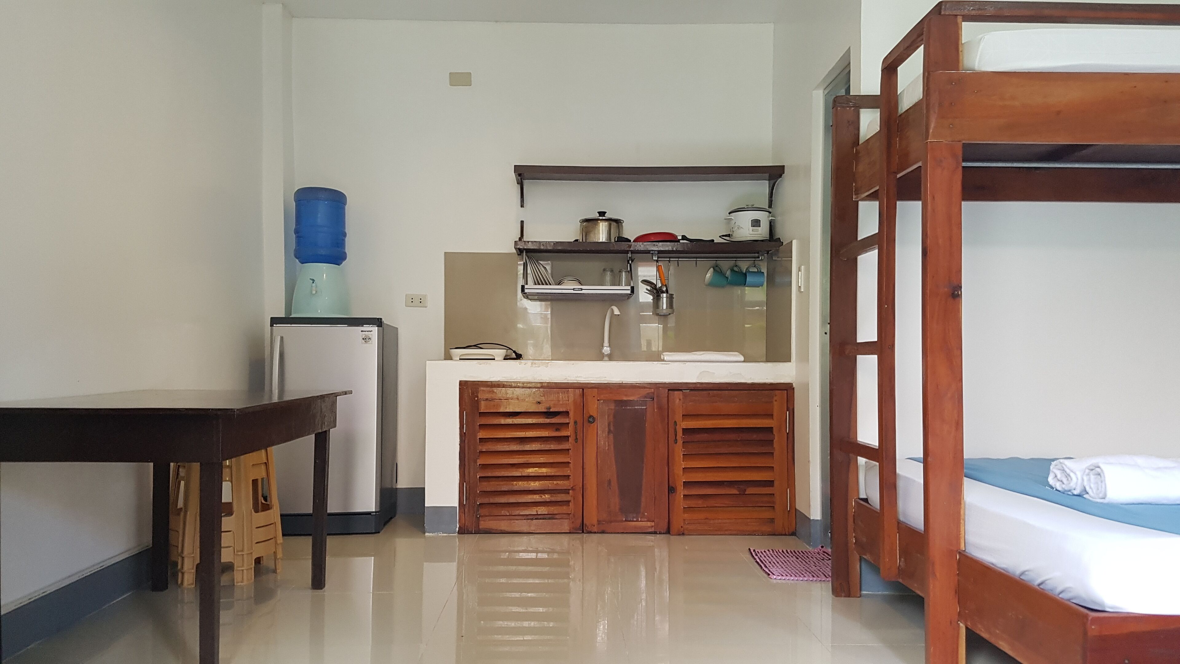 A compact kitchen with a refrigerator, sink, and wooden cabinets.