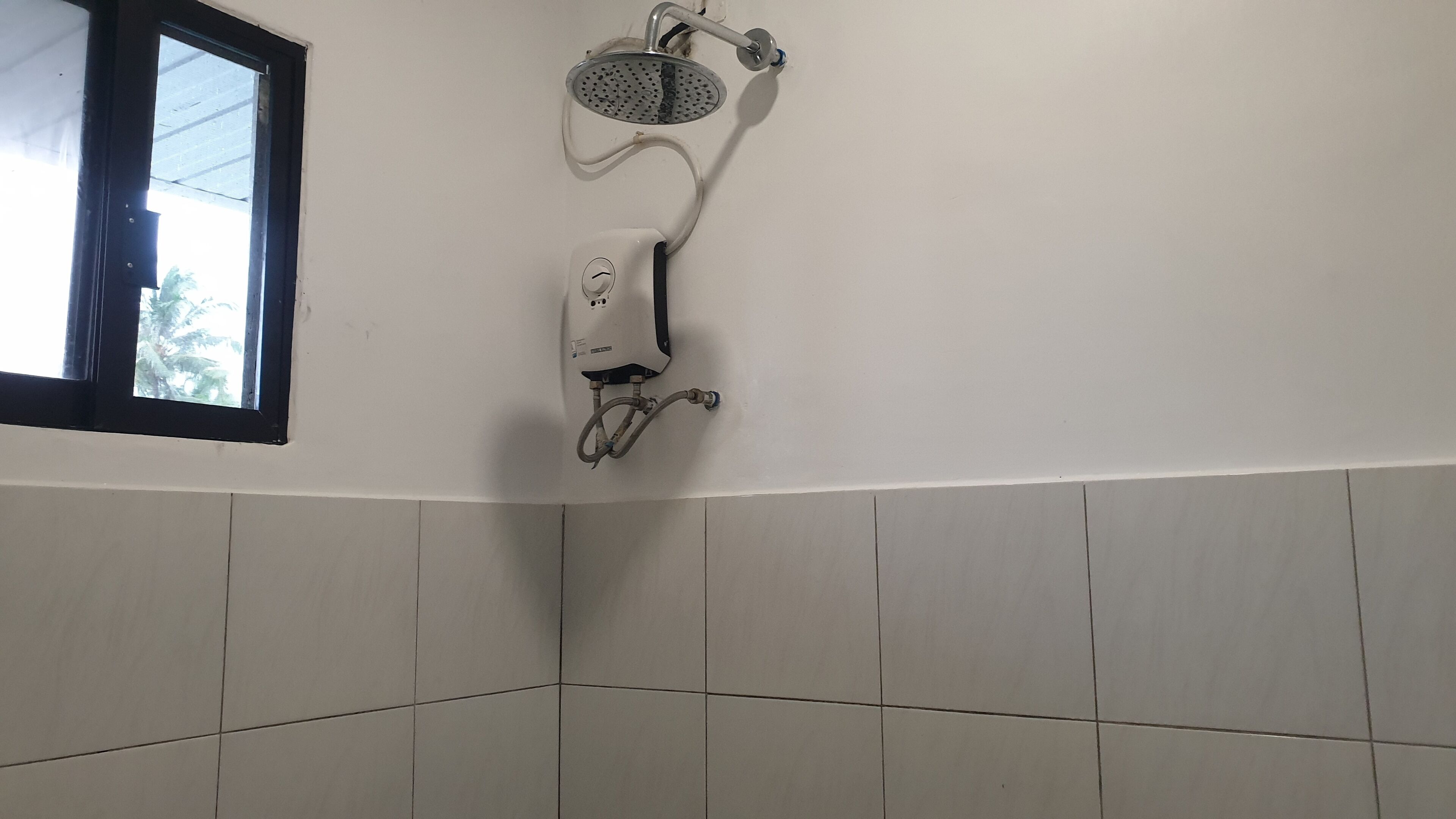 A bathroom with a shower, a window, and tiled walls.