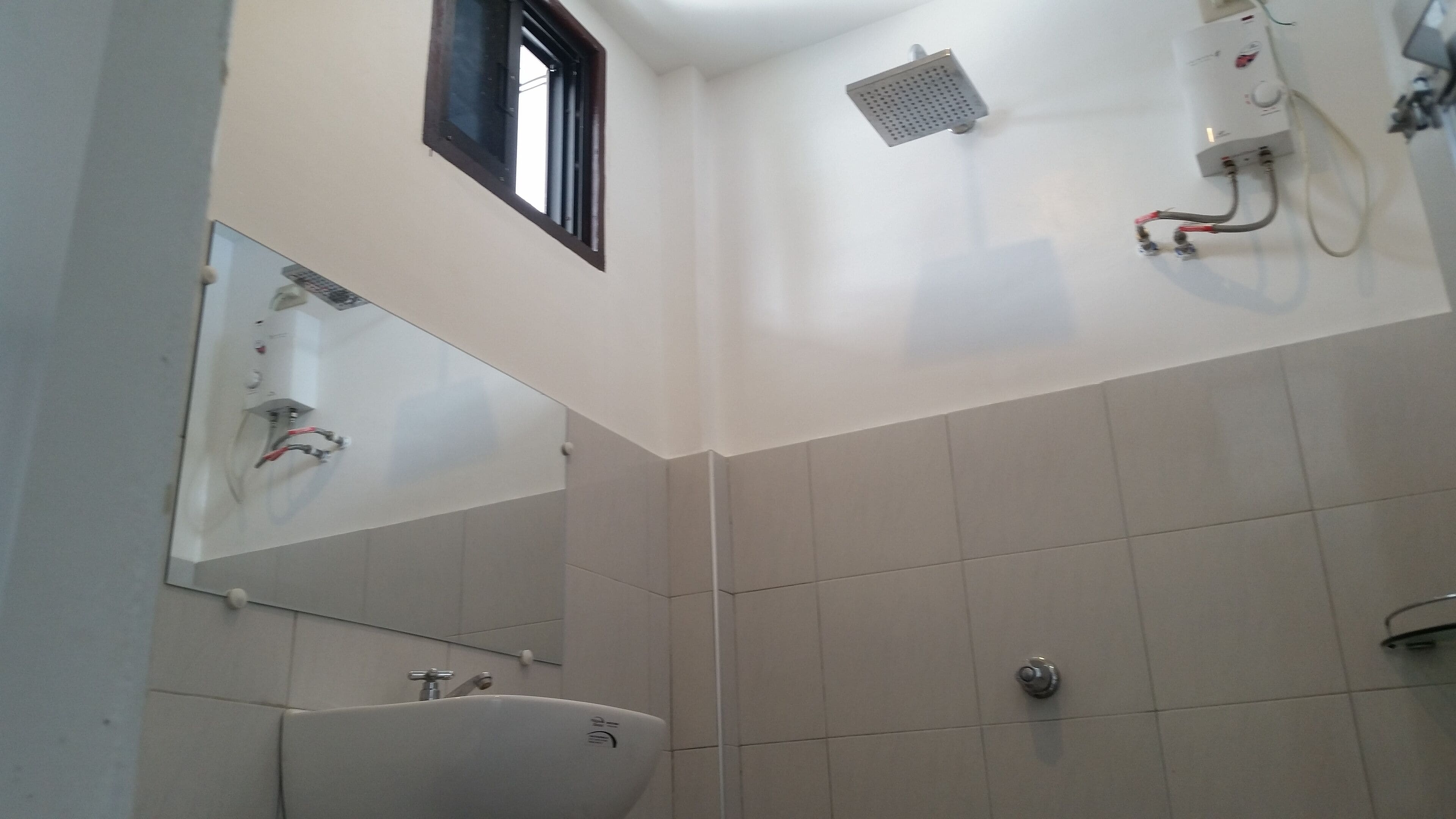 Un baño con lavabo, espejo, ducha y ventana.