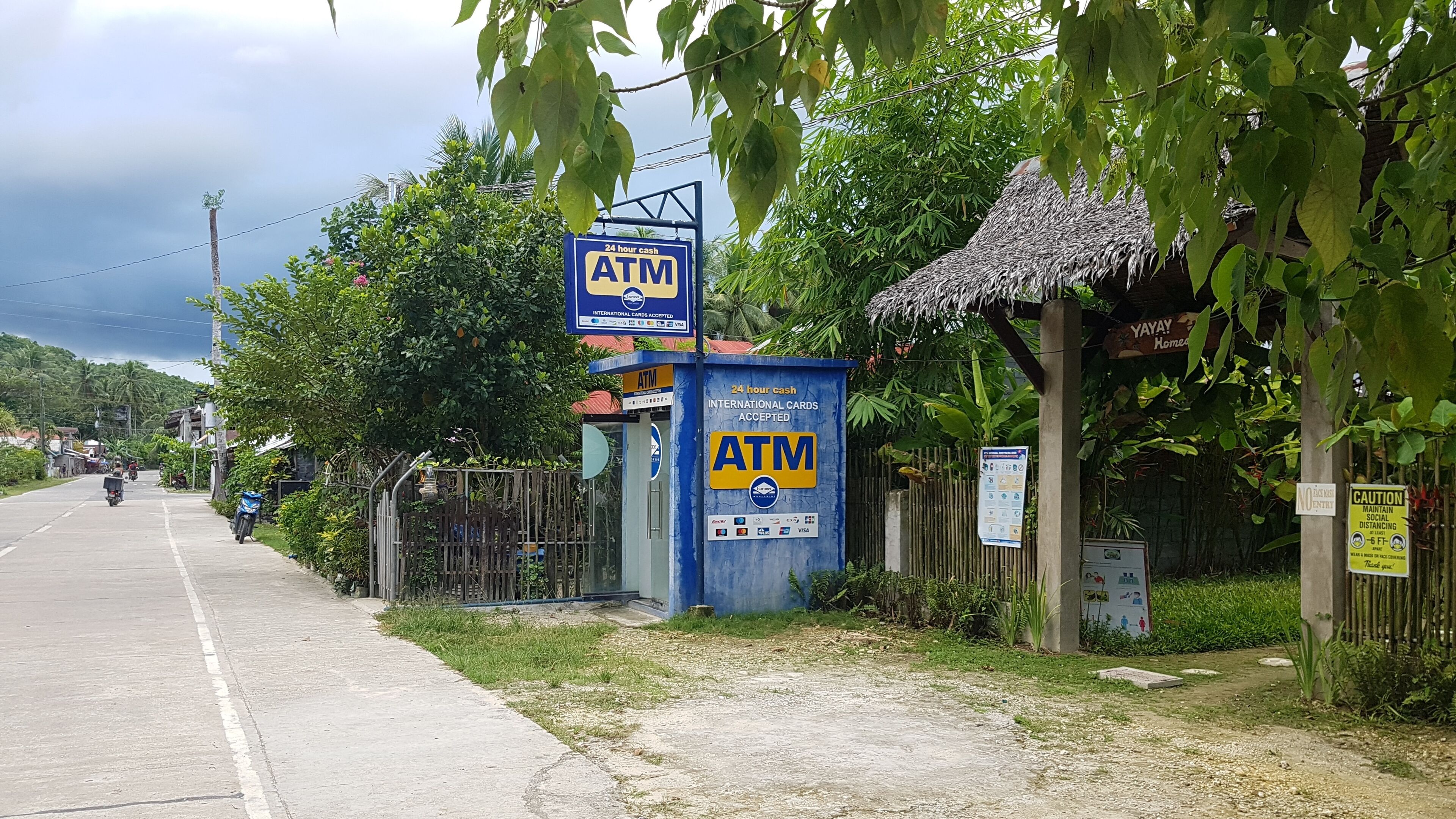 An ATM machine with a sign indicating 24-hour cash service and international card acceptance.