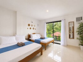 A hotel room with two beds, a large window with a view of greenery, a mirror, and a potted plant.