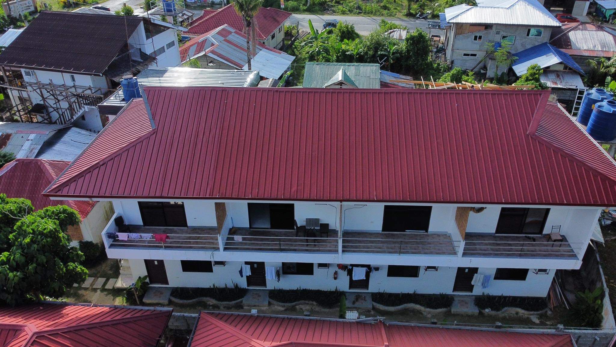 A two-story building with a red roof, surrounded by other buildings with similar roofs.