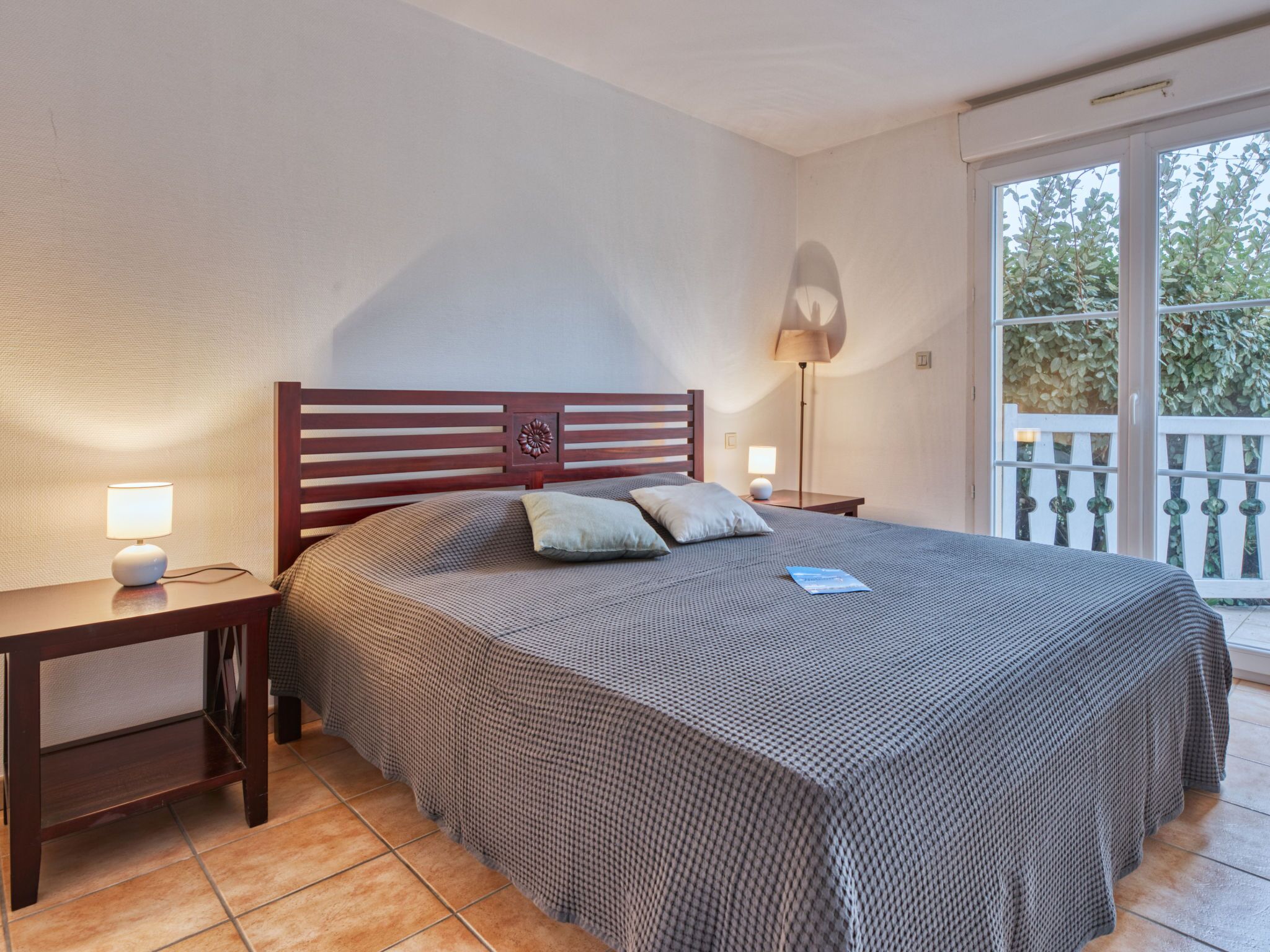 Ein Schlafzimmer mit einem großen Bett, zwei Nachttischen, einer Stehlampe und Blick auf einen Balkon.
