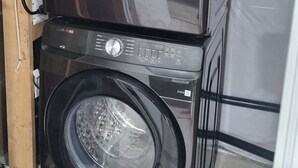 Eine gestapelte Waschmaschine und ein Trockner mit Bedienfeldern und einem Stromkabel.