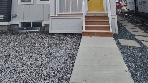 Ein zweistöckiges Haus mit weißem Veranda, einer gelben Tür und einem kleinen, weißen Geländer.