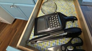 Une cuisine équipée d’un évier, d’un égouttoir, d’une râpe et d  ’une paire de ciseaux.
