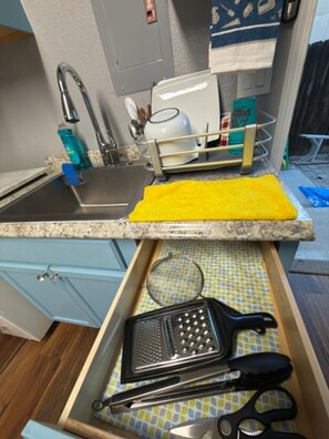 A kitchen with a sink, a dish rack, a grater, and a pair of scissors. - Charming studio near to Reno Airport (Reno)
