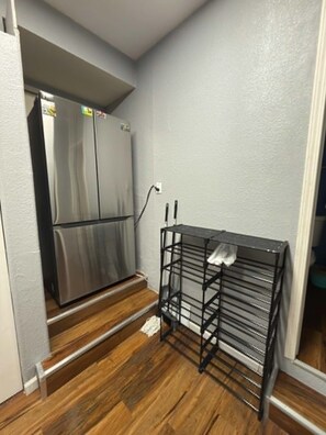 A kitchen with a stainless steel refrigerator, a black metal rack, and wooden flooring. - Charming studio near to Reno Airport (Reno)