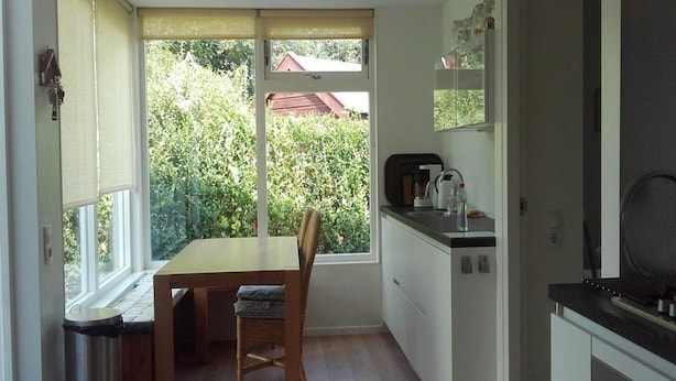 Une cuisine compacte avec une table et des chaises, un four encastré et une vue sur la verdure environnante.
