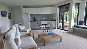 Una sala de estar moderna con un sofá, una mesa de centro y vistas a una cocina y un espacio exterior.